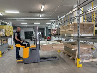 En truckförare lastar glaspartier i hyllsystem på lager.