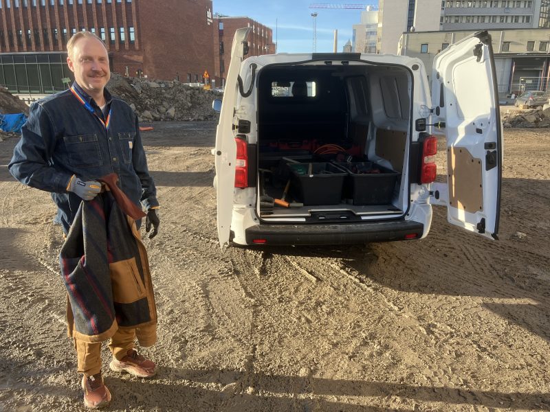 En man står bakom en skåpbil som har öppna bakdörrar.
