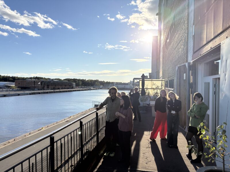 En grupp personer står på en stor balkong vid havet.